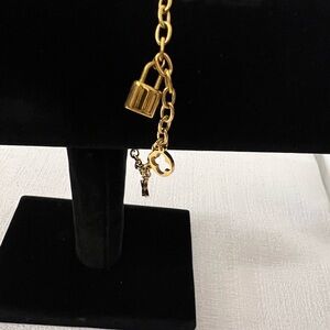 Gold-tone charm bracelet featuring a chic floral and lock design